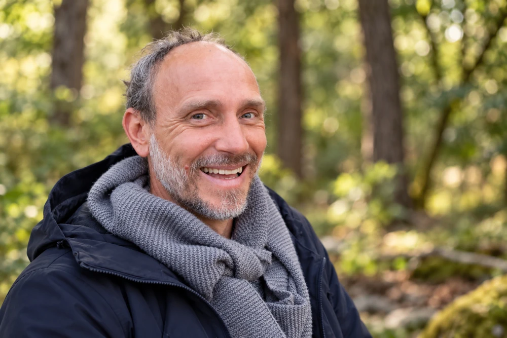 Richard Sako lächelt vor einem Waldhintergrund